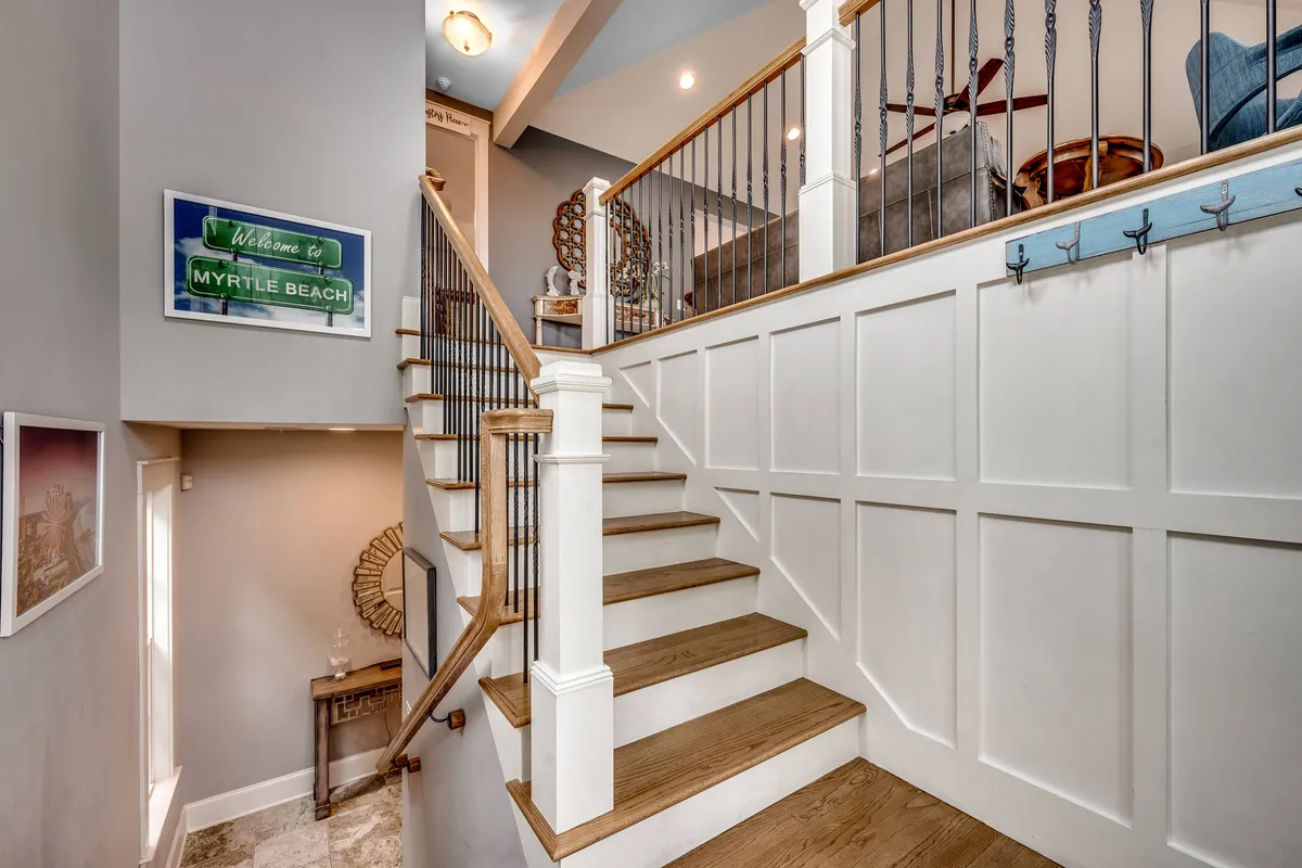 A bright, welcoming entryway featuring a staircase, a prominent 'welcome' sign, and cheerful wall art. The area feels inviting and sets the tone for a comfortable stay, suggesting easy access and a sense of arrival for guests.